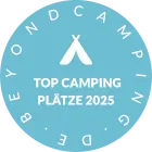 Rundes Abzeichen in Blau mit dem Text 'Top Camping Plätze 2025' und einem Zelt-Symbol in der Mitte.